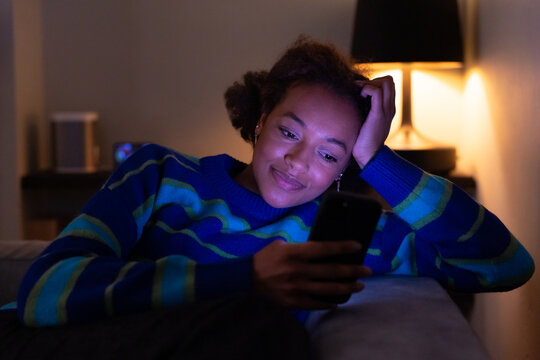 Woman Relaxing and Texting on Mobile Device in Evening