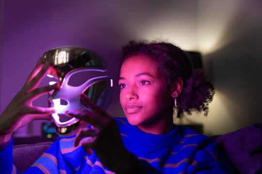Woman holding a LED Light Mask at Home