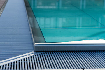 View of the corner of a swimming pool with turquoise water and a mesh edge