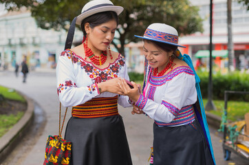 Indigenous riobamba women wearing traditional clothes using smartphone in ecuadorian andes city