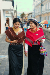 Indigenous otavalo women wearing traditional clothes walking in ecuadorian town
