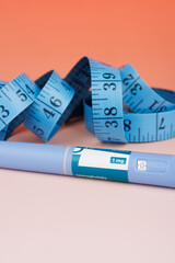 Diabetes and obesity concept with semaglutide pens and measuring tape on red background