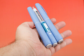 Semaglutide injection pens held in hand against red gradient for diabetes and obesity treatment...