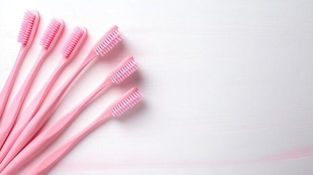 An array of bright pink toothbrushes neatly aligned on a white surface, representing daily dental hygiene and the importance of oral care in maintaining a bright smile.