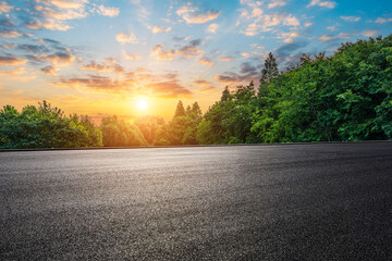 Empty asphalt road and green forest with beautiful sky clouds at sunset