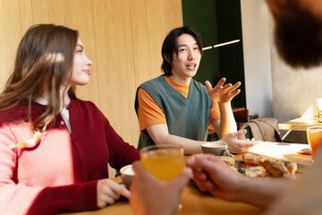 Asian man explaining something to his friends during lunch break at the cafe