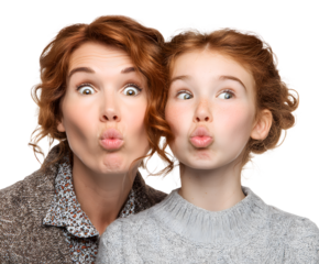 A mother and daughter make funny faces, puckering their lips and looking at the camera together.