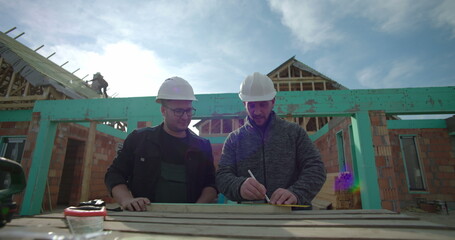 Builders working on precise measurements, construction site, collaborative residential project,...