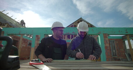 Builders working on precise measurements, construction site, collaborative residential project,...
