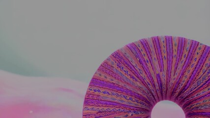 Abstract purple patterned donut-shaped object against a soft background, creating a visual illusion with stripes and vibrant colors, artwork.