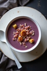 Purple creamy soup with croutons and chopped toppings