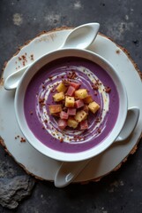 Purple soup with ham and croutons in white bowl