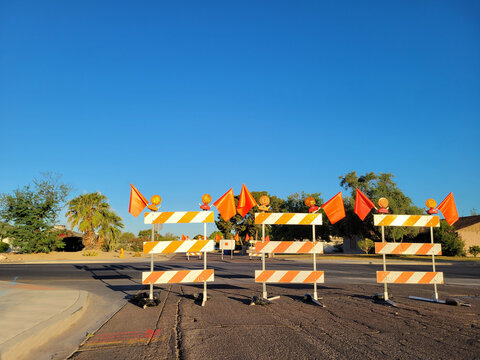 Bright yellow lights mounted on top of highly visible traffic control barricades along with warning red flags in front of road segment scheduled for maintains work
