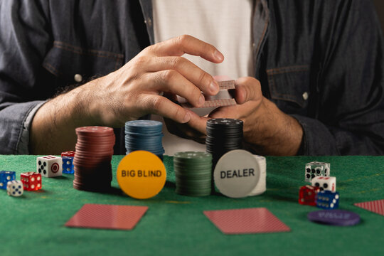 Player Concentrating on Card Game at Poker Table Surrounded by Chips, Dice, and Game Accessories in a Cozy Gaming Environment