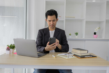 Fototapeta premium A man is typing on a laptop at a desk with a calculator, a notebook, and a stack of books. Concept of productivity and focus, as the man is working on a task that requires concentration 