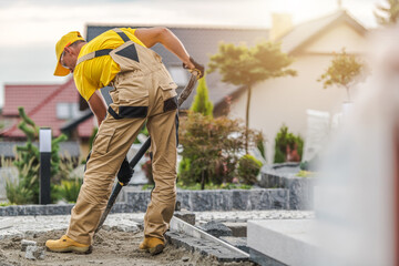 Skilled Worker Laying Concrete at a Residential Property During Late Afternoon in a Suburban Area