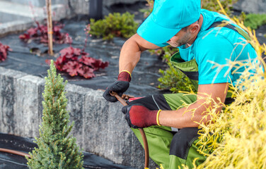 Gardener Repairing Irrigation System in a Landscaped Garden During Sunny Afternoon
