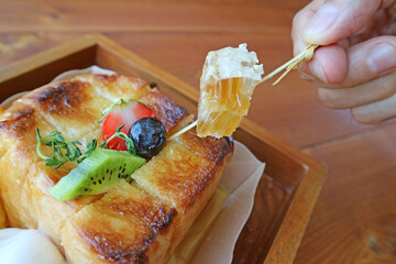 Hand Picking Up a Slice of Mouthwatering Honeycomb from Honey Toast