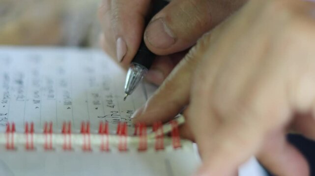 A hand writing on a notebook