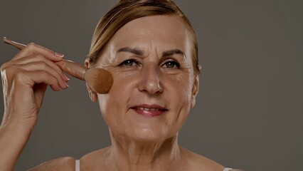 Mature Woman Applying Makeup with Brush for Flawless Look