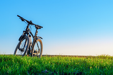 Bicycle on green grass at sunset. Front view. Cycling concept. Image for adding text message.