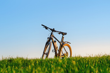 Bicycle on green field at sunset. Low angle view. Cycling concept. Image for adding text message.