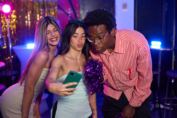 Friends taking selfie at nightclub party with cheerleader pompoms