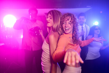 Two female friends dancing together at a nightclub party