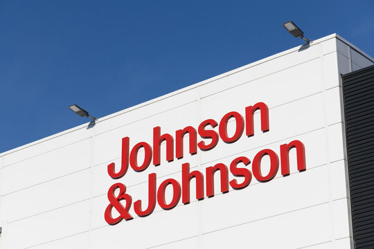 The red Johnson & Johnson logo stands prominently on the white facade of a modern corporate building under a clear, vibrant blue sky. Leiden, Netherlands, 3 May 2025