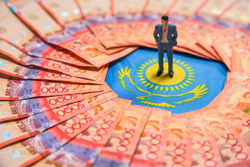 The figure of a businessman stands on the Kazakh flag among tenge banknotes