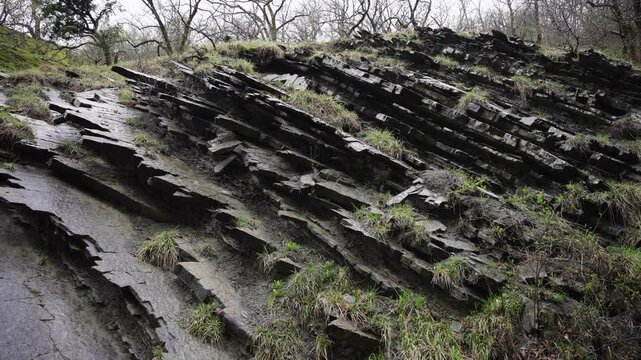 An angled view reveals geological strata on a rocky riverbank, showcasing erosion and sediment patterns.