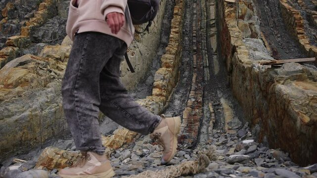 A close view of angled sedimentary rock layers eroded into parallel ridges along the seaside.