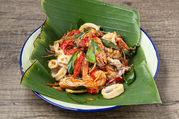A vibrant and aromatic plate of Pad Cha Thale, a Thai stir-fry with mixed seafood and fragrant...