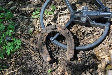old rusty horseshoe found by a metal detector. rusty horseshoe and metal detector coil close-up. metal detector search concept