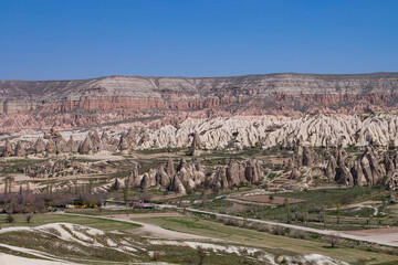 Fototapeta premium Aerial and panoramic view of the stunning and unique nature and rock formation, fairy chimneys of Cappadocia, Goreme, Turkiye on a beautiful spring blue sky day 