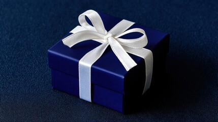 Elegant navy blue gift box with white ribbon and bow presented against a contrasting dark textured background.
