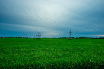 Expansive Green Field with Distant Power Towers and Cloudy Sky