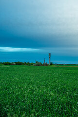 Rolling Green Field with a Prominent Water Tower Against the Sky