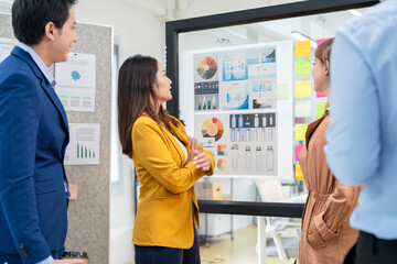 Asian business woman with friend In a modern office setting, a group of coworkers collaborate on renewable energy solutions, focusing on ESG principles and sustainable business practices