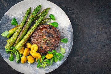 Grilled green asparagus with beef burger patty, gnocchi and fresh green salad
