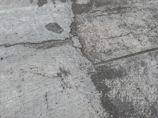 Cracked and scratched concrete road surface with rough texture and aged urban pattern