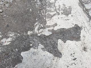Worn concrete surface with cracked texture and exposed dirt on damaged urban pavement
