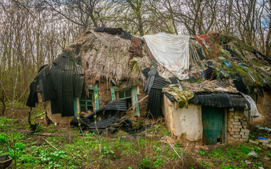 Rustic Derelict Building with Improvised Roofing and Small Attached Structure