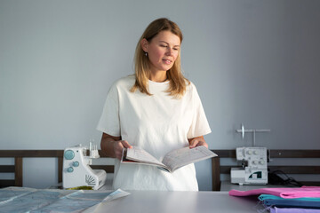 Woman in a sewing workshop reading a pattern guide