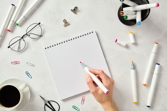 Top view of artist's hands sketching with markers on a marble table