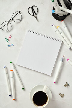 Top view of a sketchbook and markers on a marble table