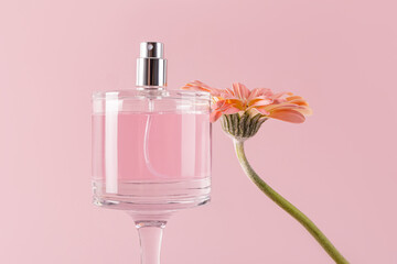 Elegant perfume bottle and flower on pink background