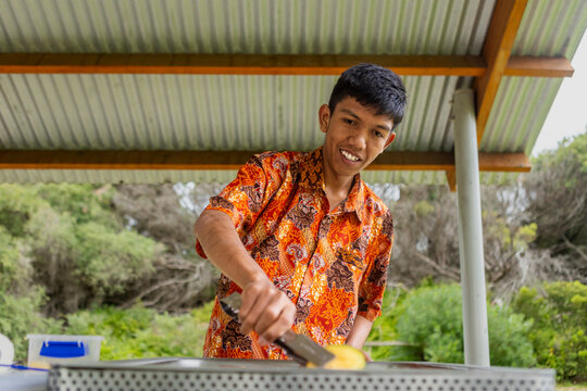Indonesian person in Australia cooking outdoors in batik attire