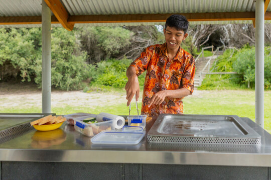 Indonesian enjoying outdoor cooking in batik attire