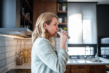 Businesswoman drinking fresh water in modern kitchen